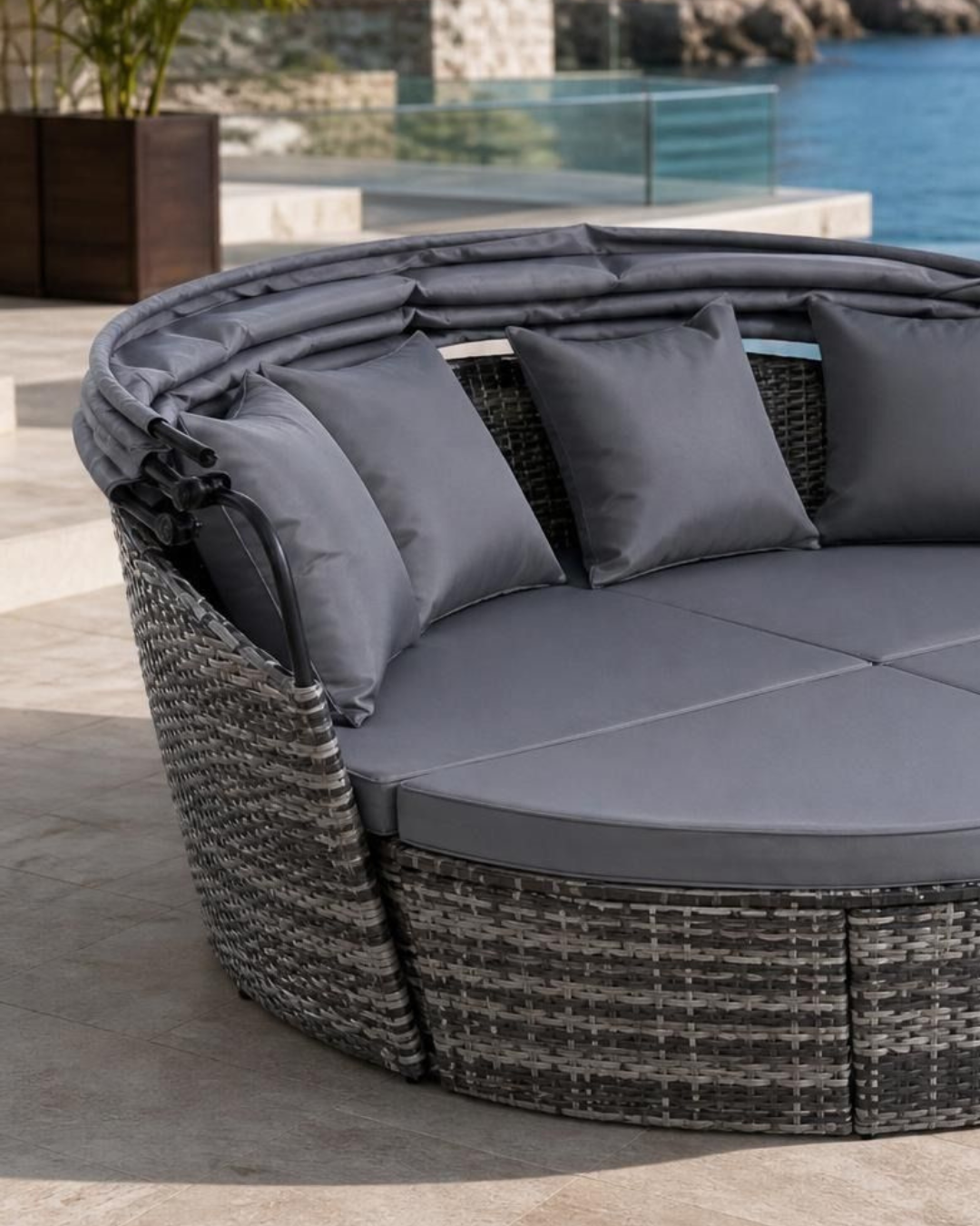 Round grey rattan day bed with gray cushions on a patio