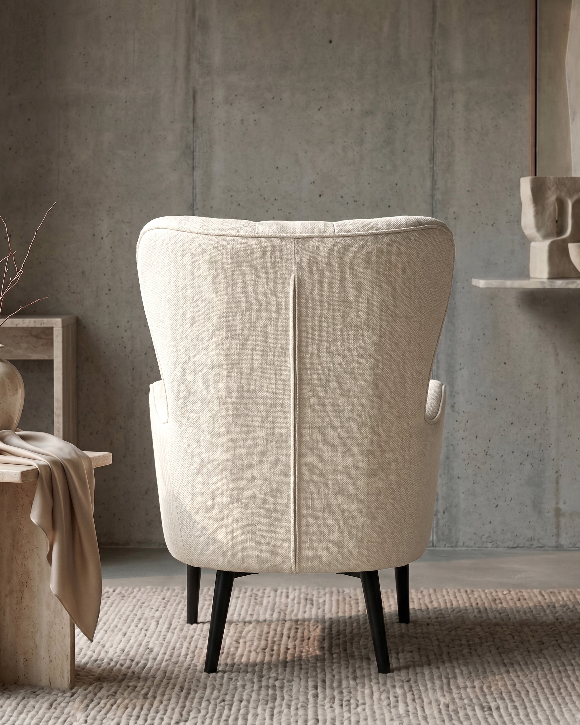 Cream wingback armchair in a room with concrete wall and wooden table