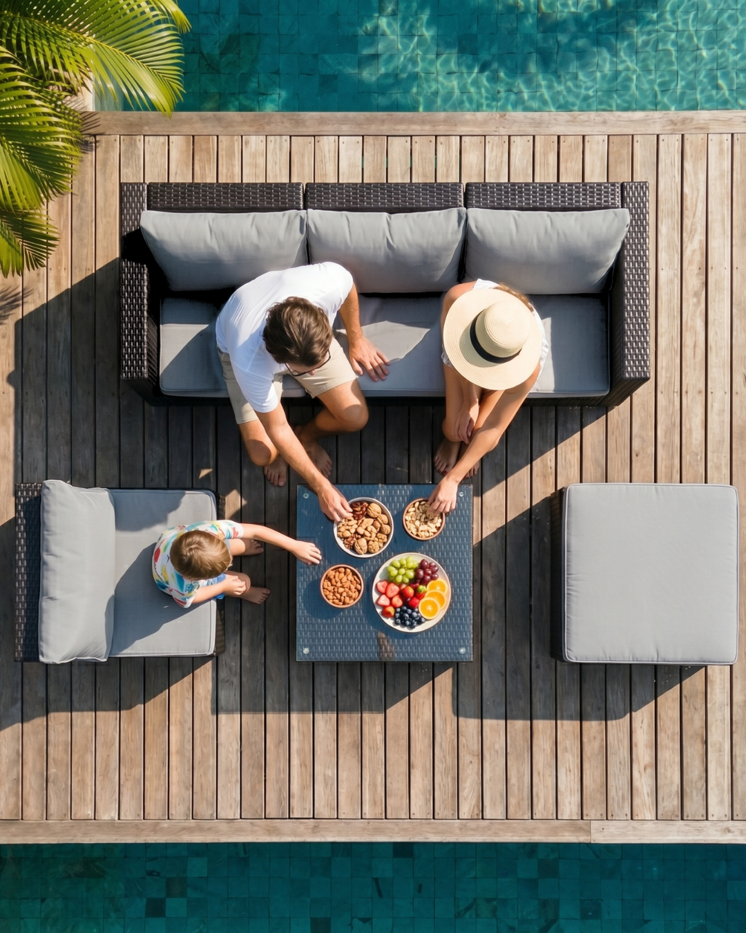 Family enjoying a meal on a black rattan garden furniture set by the pool