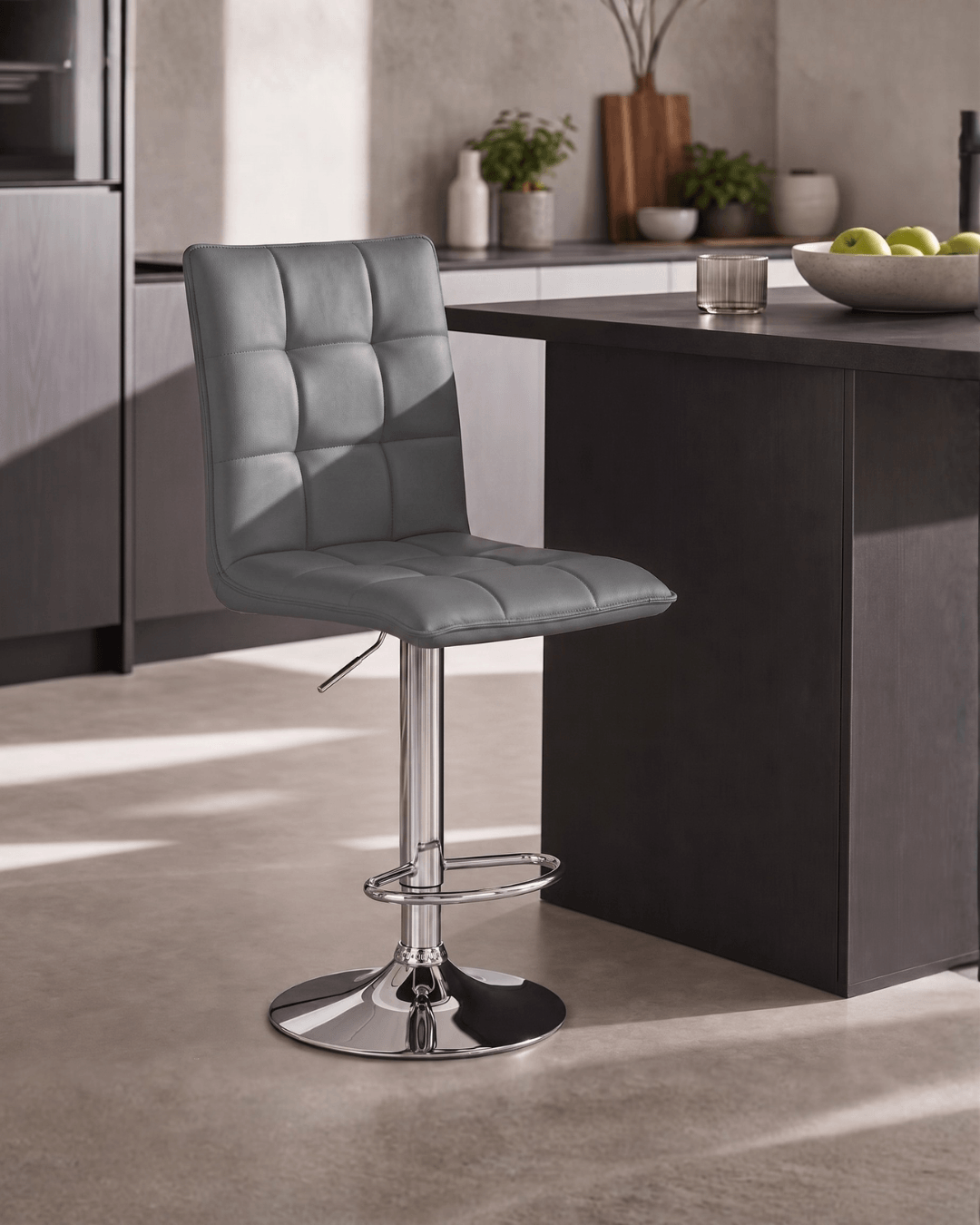 A modern grey upholstered bar stool with a tall backrest and chrome pedestal base