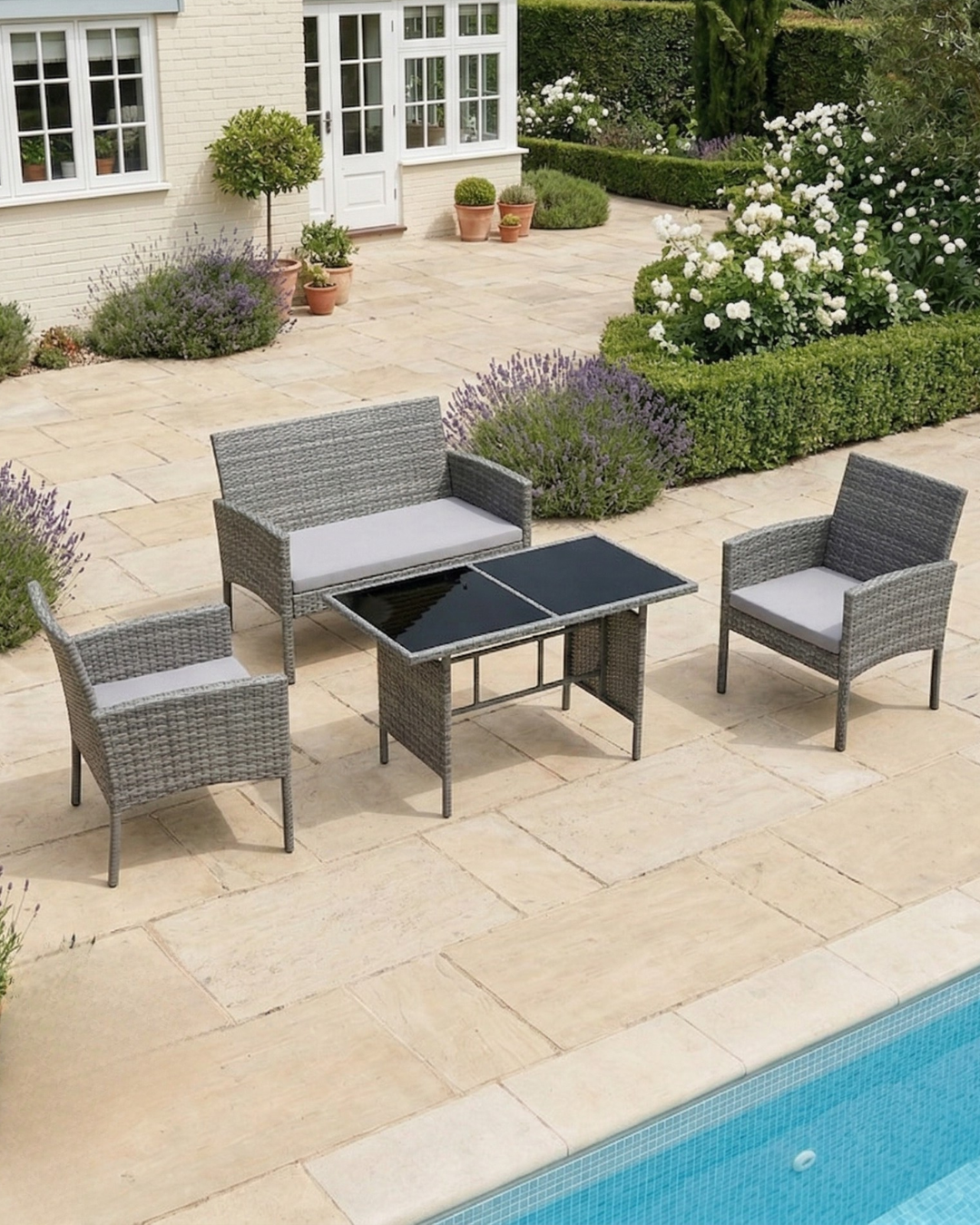 Grey rattan dining set with cushions on a stone patio by the pool