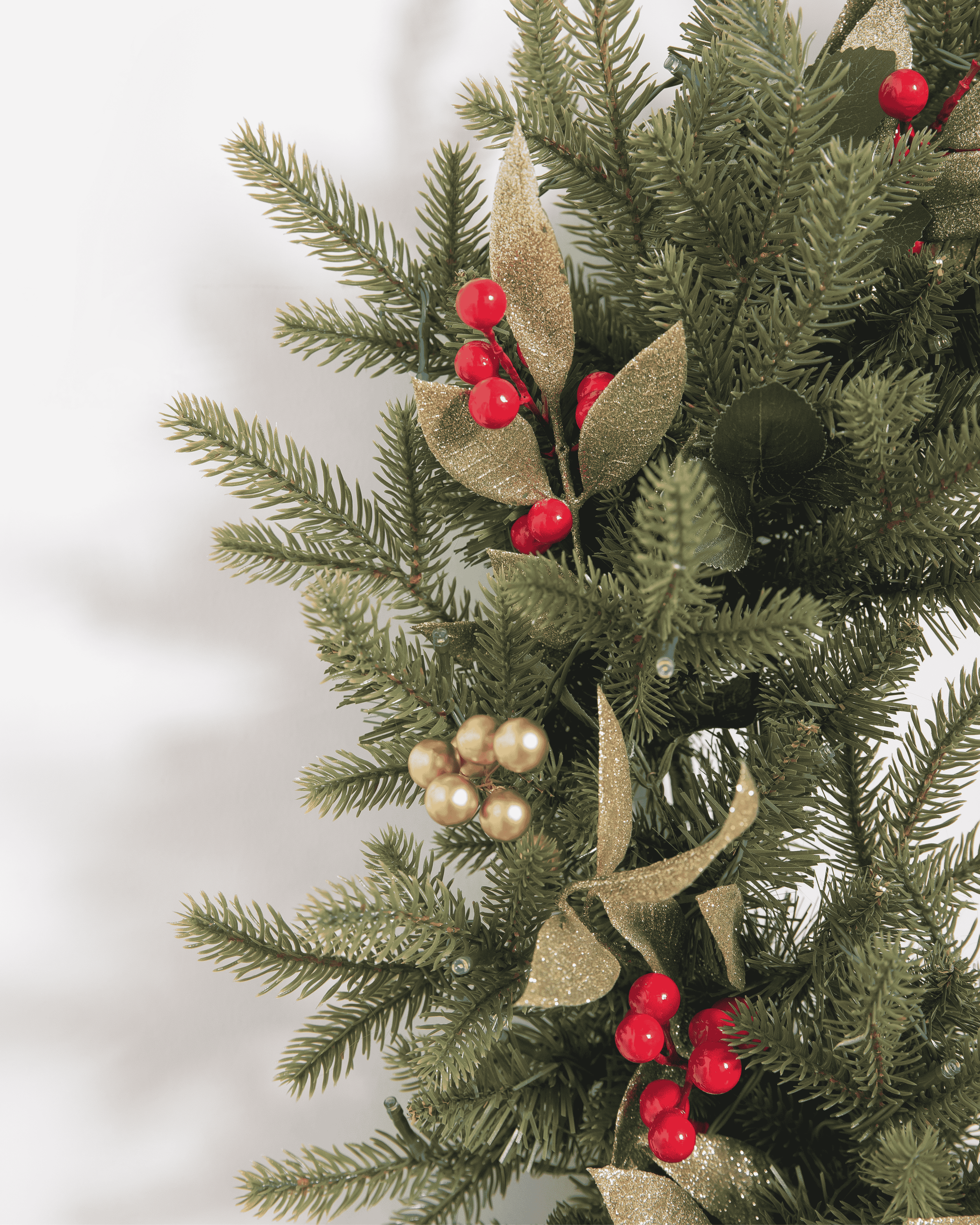 Decorative Christmas garland with greenery, red berries, and gold leaves