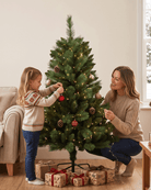 Mother and daughter decorating a Canada Spruce artificial Xmas tree by the sofa