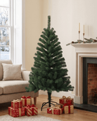 A small artificial Christmas tree stands at 4ft height in a living room beside a fireplace, with wrapped gift boxes placed at its base.
