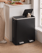 A large black kitchen pedal bin with an open lid, placed on a wooden floor next to a kitchen counter