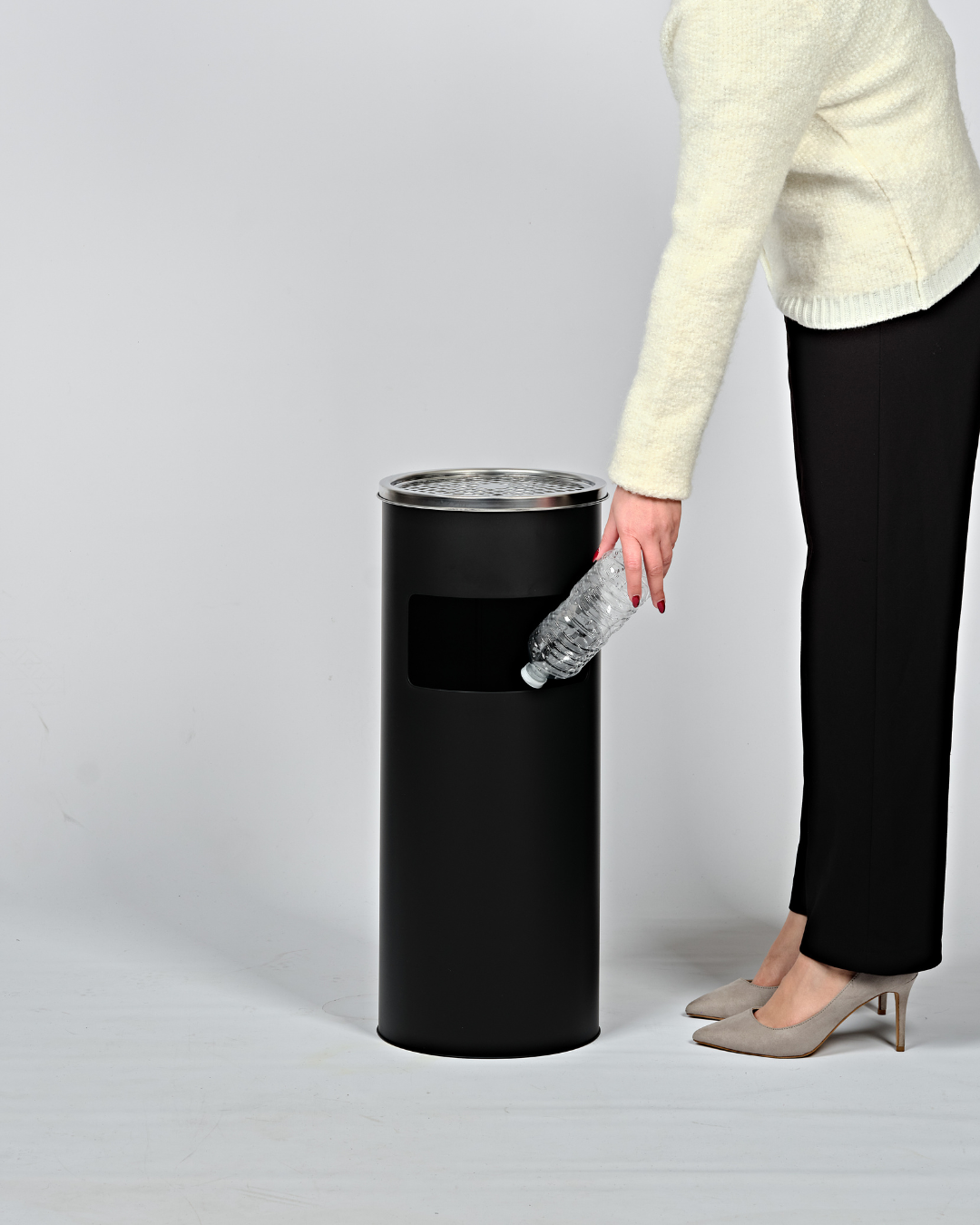 Person disposing of a plastic bottle into a black bin