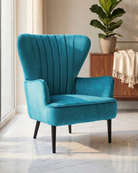 Teal velvet armchair in a room with a plant and wooden cabinet.