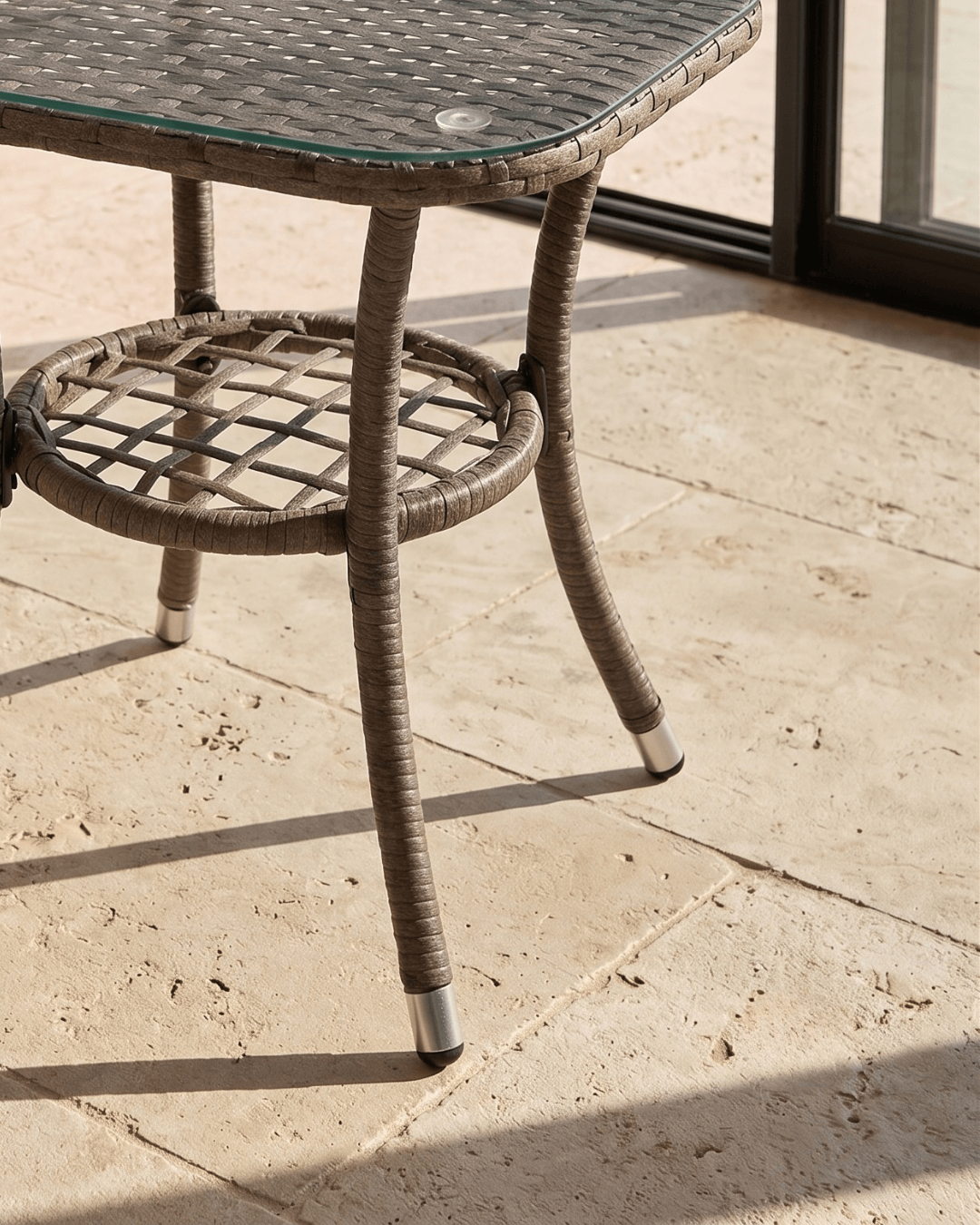 Outdoor patio side table with a woven wicker-style frame, beveled edges, glass top, and lower shelf