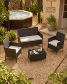 Four-piece outdoor patio furniture set including a loveseat, two armchairs, and a coffee table with seat cushions