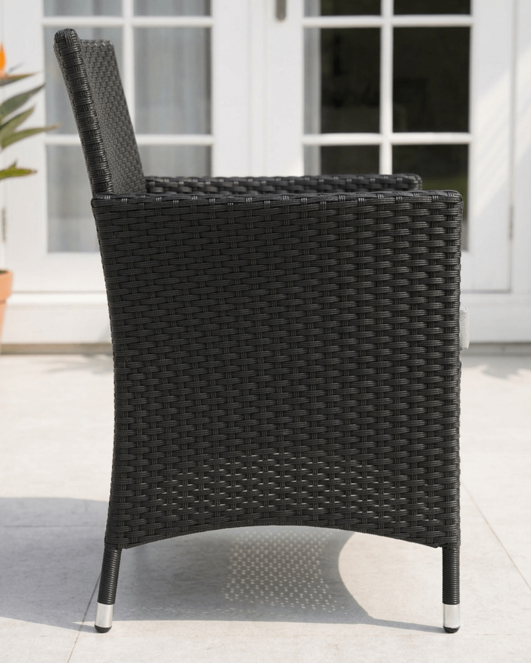A black woven rattan outdoor patio armchair shown from the side