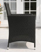 A black woven rattan outdoor patio armchair shown from the side