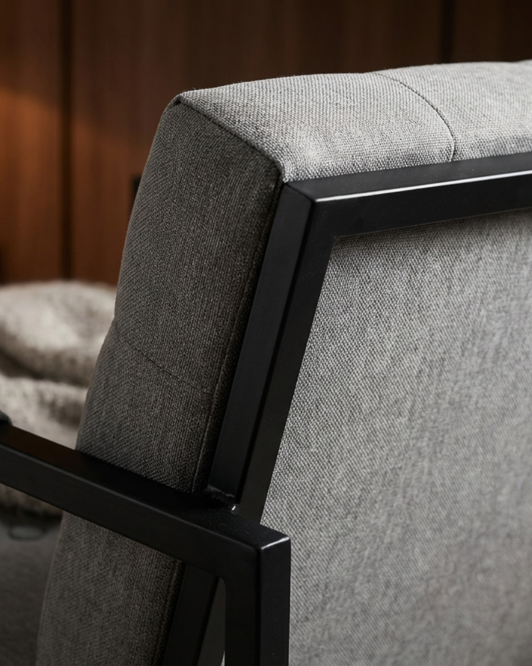 Grey upholstered cushion chair with black metal frame