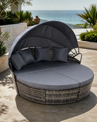 Round outdoor daybed with canopy on a patio with ocean view