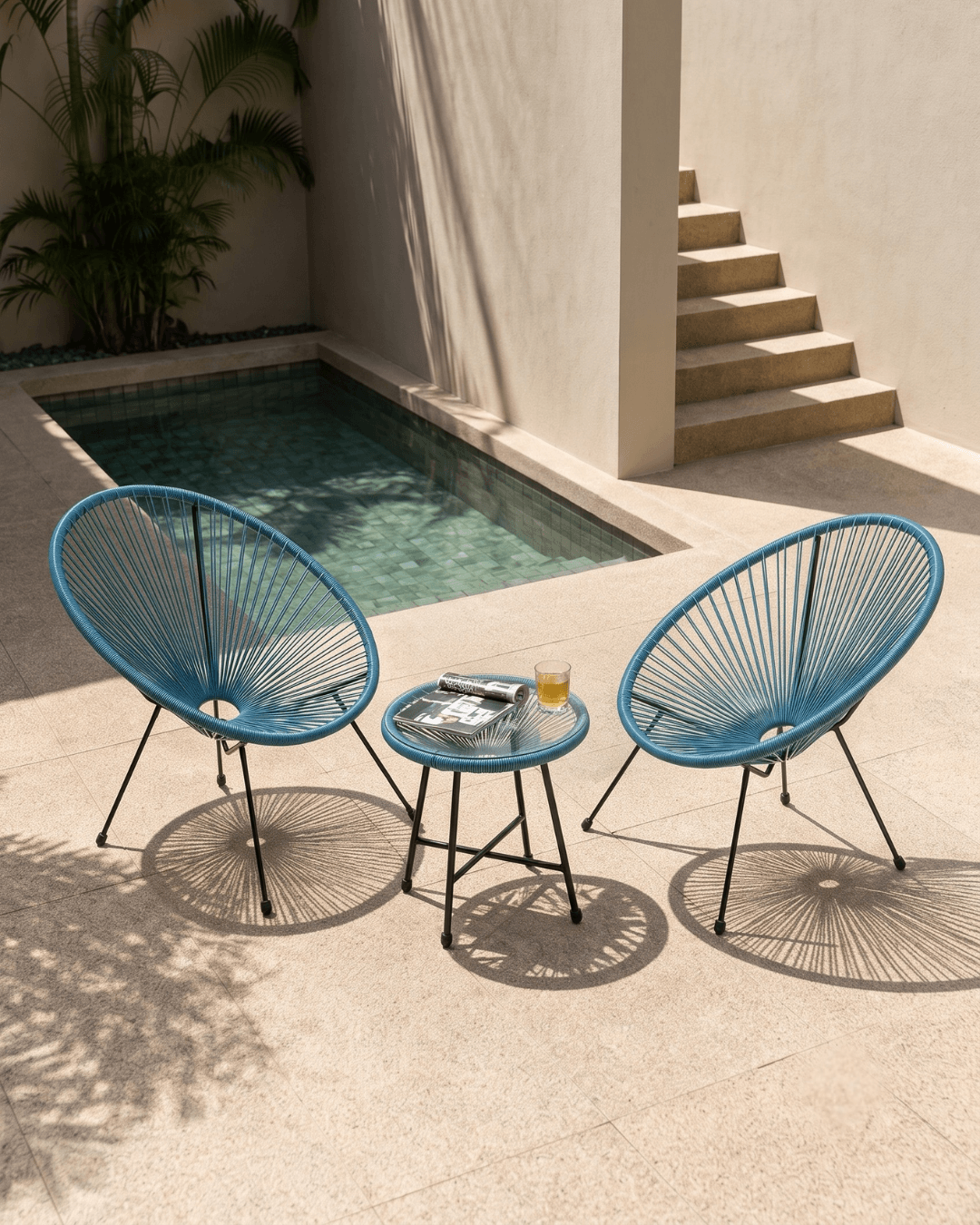 Teal blue egg chair set on a stone patio