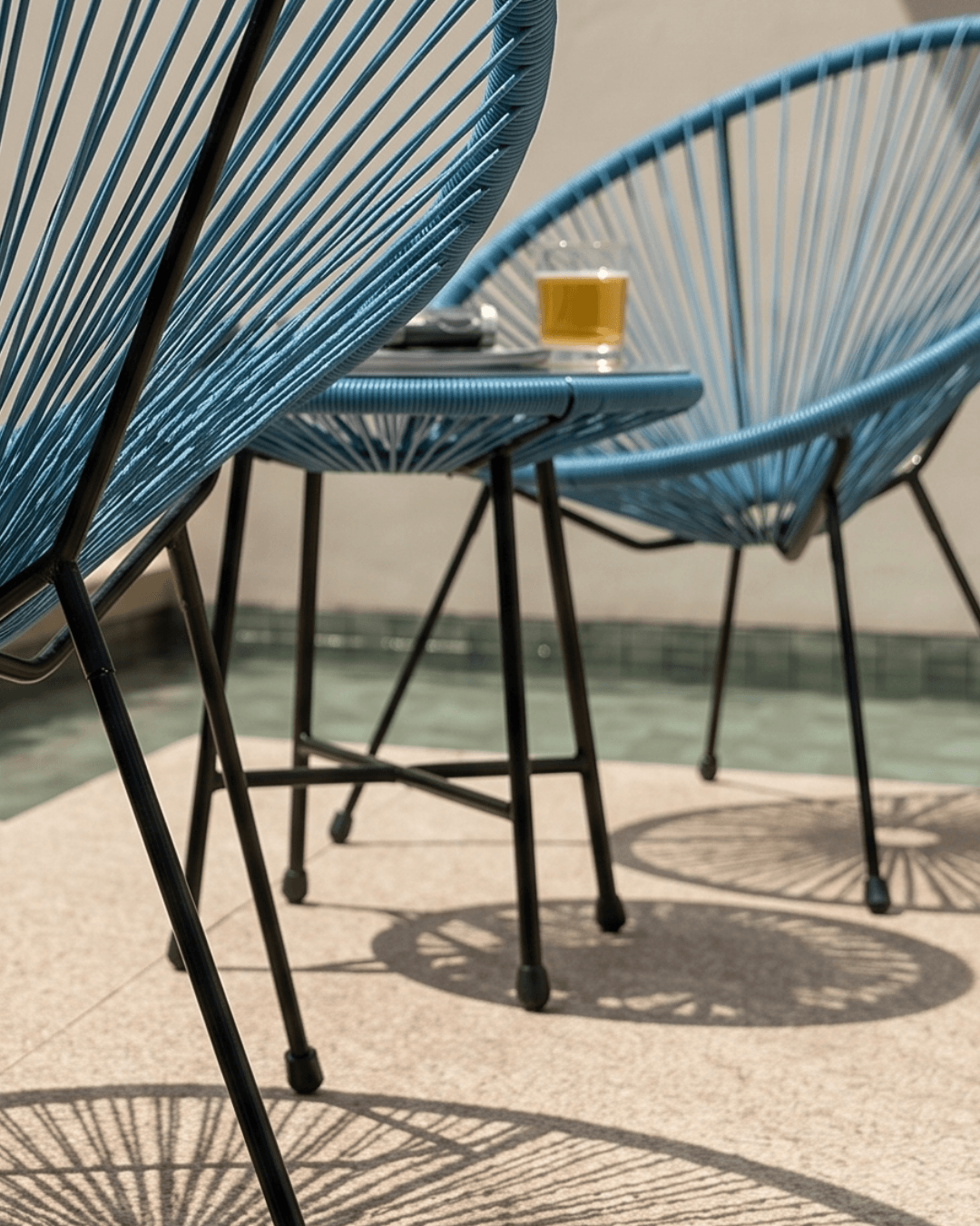 Blue woven outdoor patio chairs with black metal legs and a matching small round side table