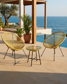 Outdoor patio set with two yellow chairs and a small table on a deck overlooking the ocean