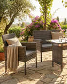 Outdoor patio set with wicker chairs and table on a stone patio