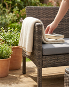 Book on a wicker bench with a blanket resting on the armrest