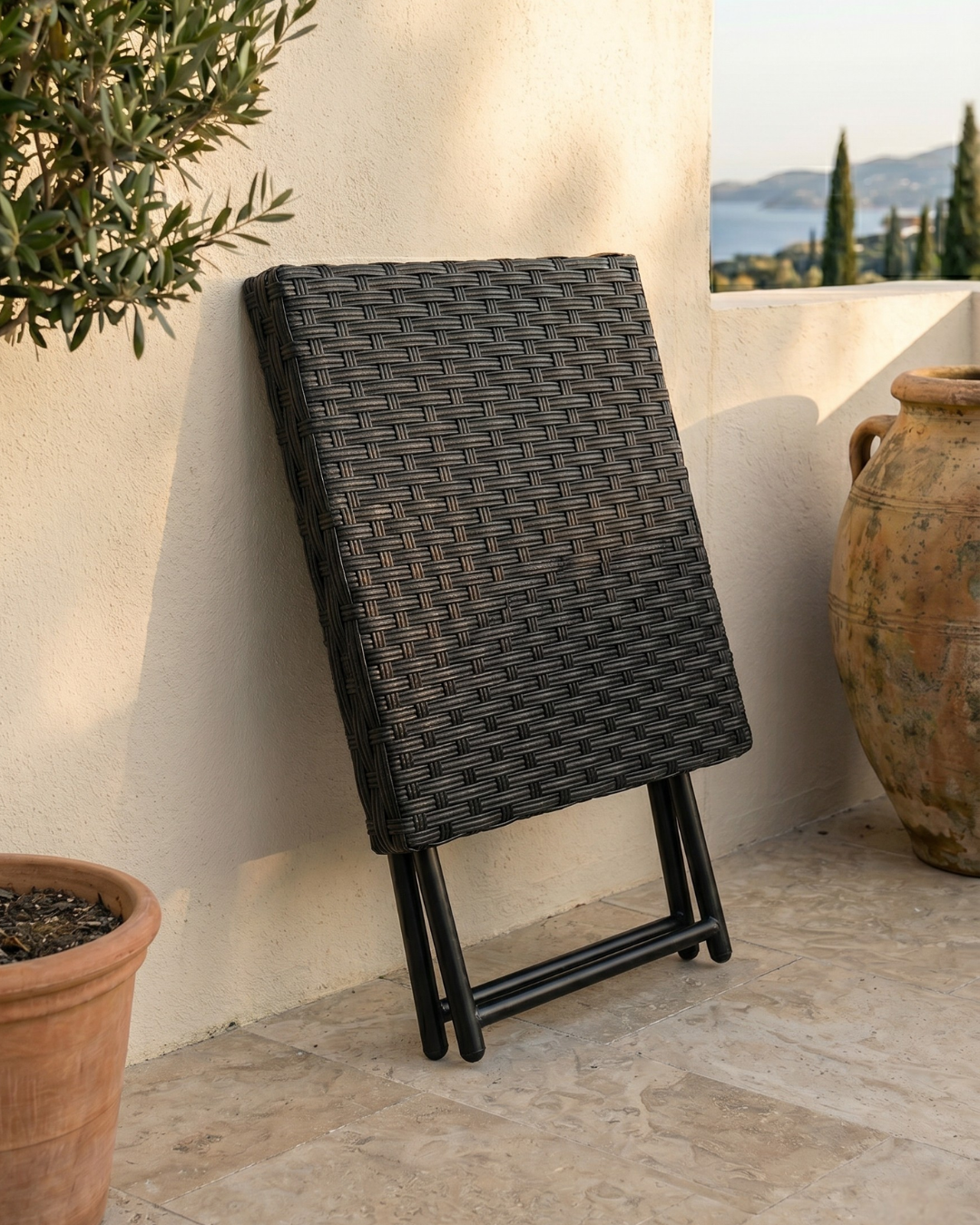 Black rattan folding table leaning against the wall