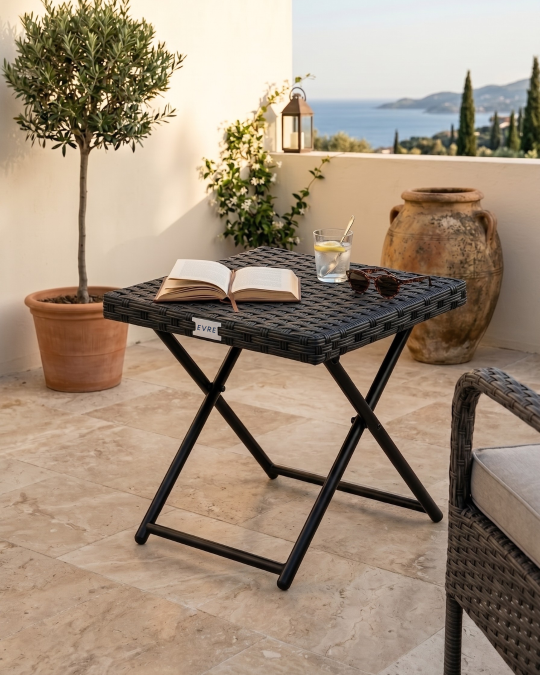 Outdoor setting with a small folding table, book, and glass of lemonade on a patio