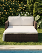 Brown rattan sofa bed with cream cushions by the pool