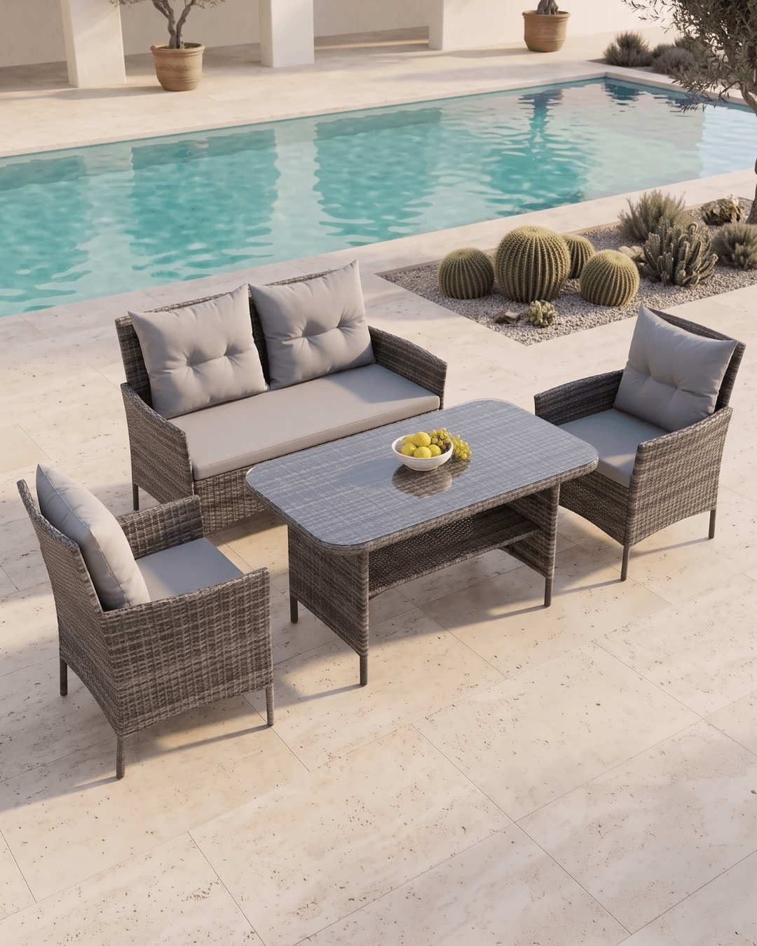 A 4-piece outdoor dining set with a gray wicker sofa, two matching armchairs and a rectangular brown wicker dining table arranged on a stone patio next to a swimming pool