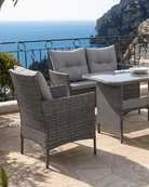 Patio dining set featuring a loveseat, grey rattan armchair and a glass-topped dining table with practical under-table storage shelf built in