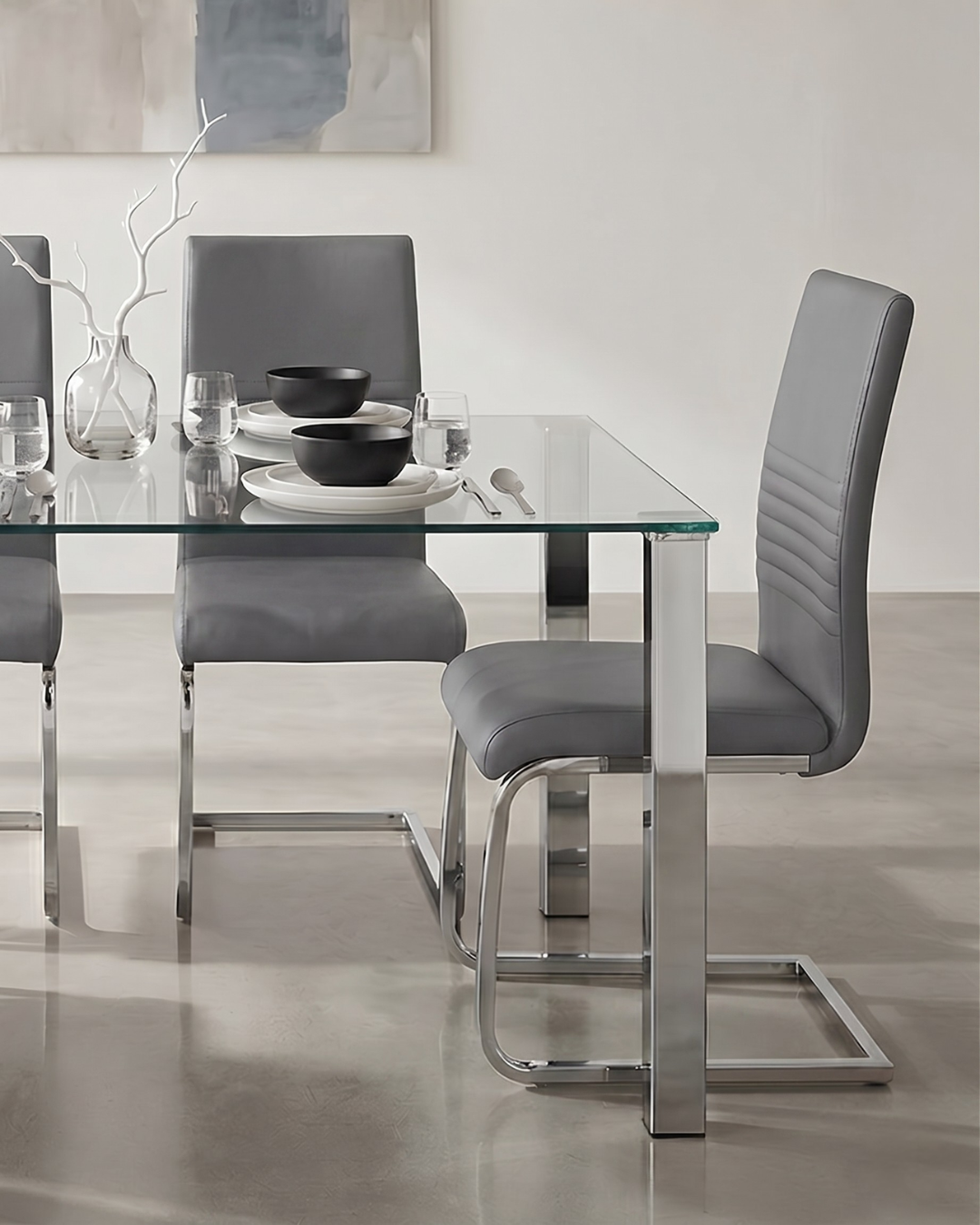 Dining table set with glass top and metal legs, surrounded by gray chairs in a modern kitchen