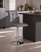A modern grey upholstered bar stool with a tall backrest and chrome pedestal base