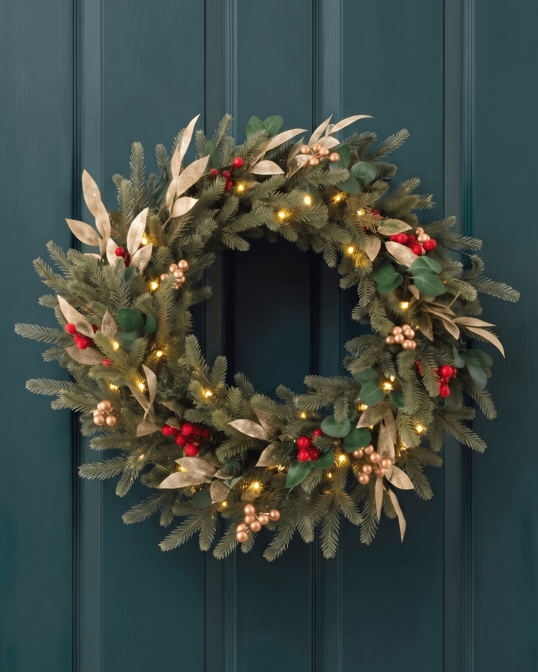 Pre-lit Christmas wreath with golden and red berries and LED lights on the front door