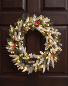 Artificial frosted tips Christmas wreath with warm white lights, pine cones and winter berries on a door