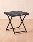 A small garden table in grey rattan with a folding metal frame