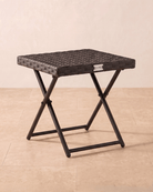 A square small rattan garden table with a folding metal frame