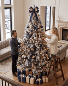 A couple decorating an 8ft large snowy Christmas tree