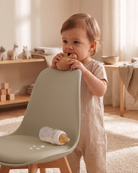 Spilt milk bottle on PU leather seat on taupe tulip chair