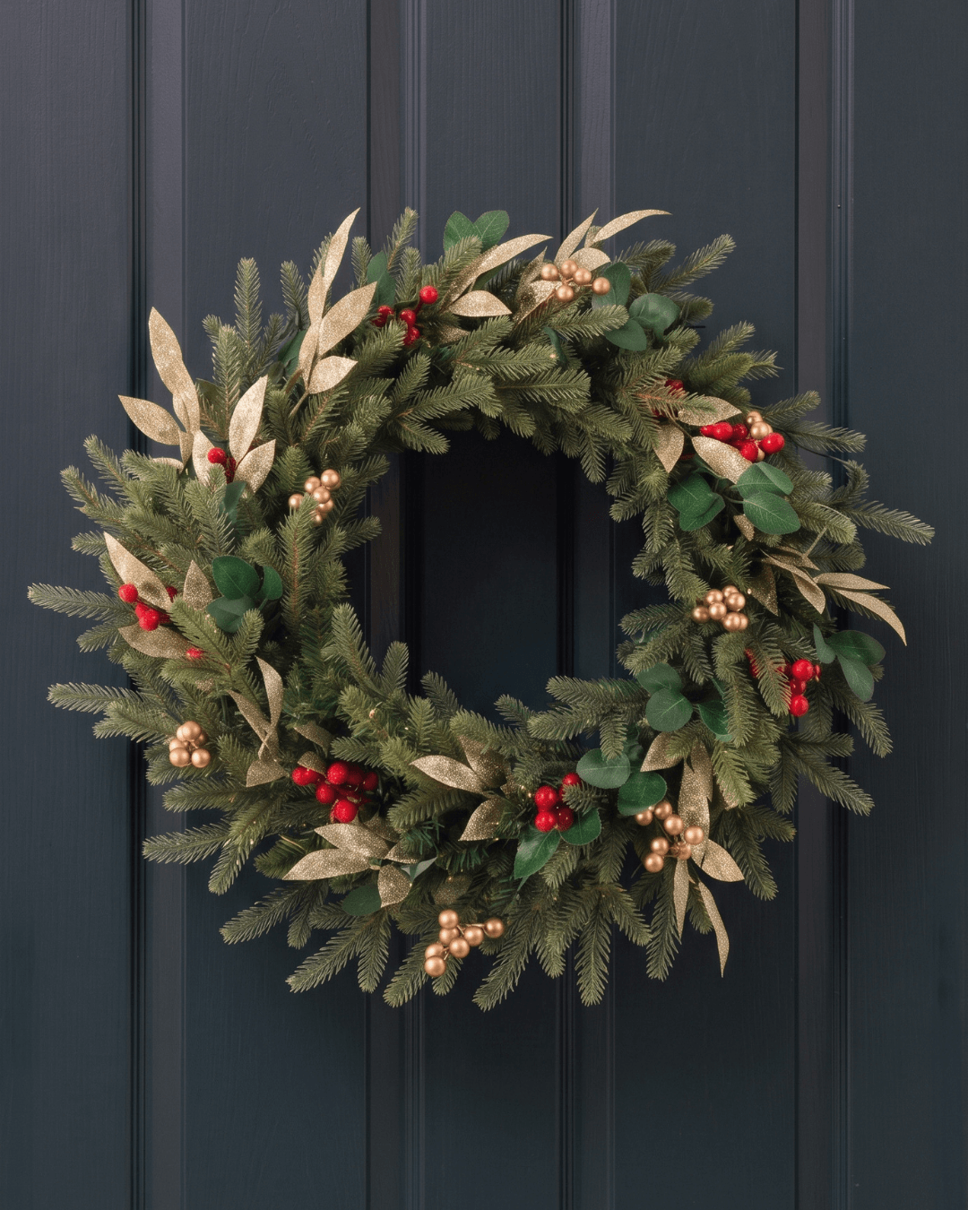 Christmas wreath with faux leaves, and red and gold berries on a panelled door