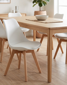 Dining room with white chairs around a wooden dining table on a wooden floor