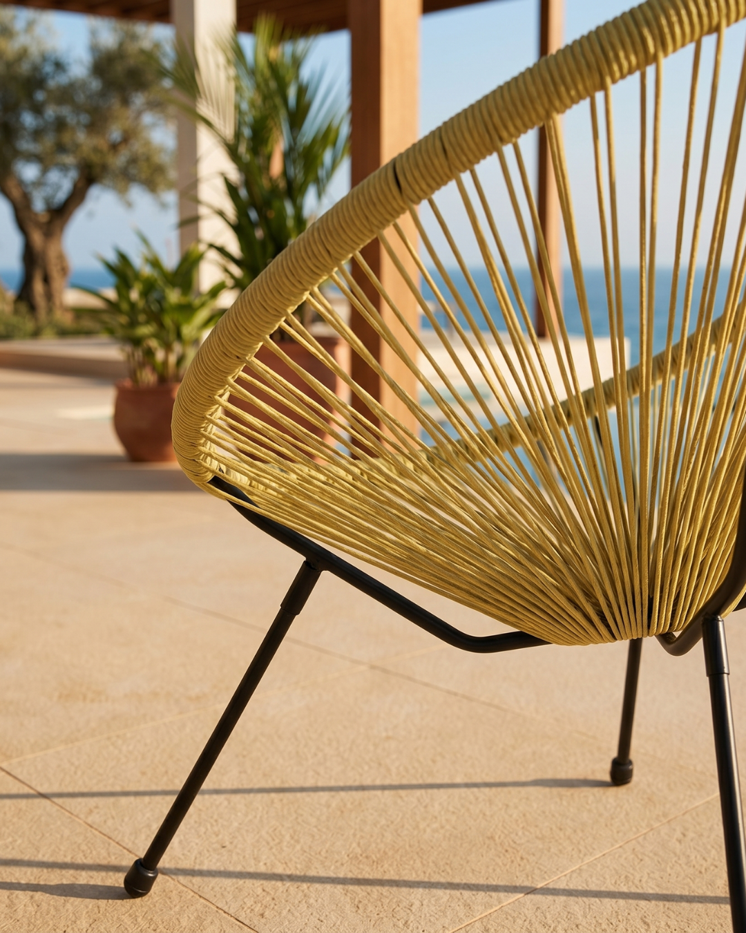 Yellow woven egg chair on a patio with ocean view